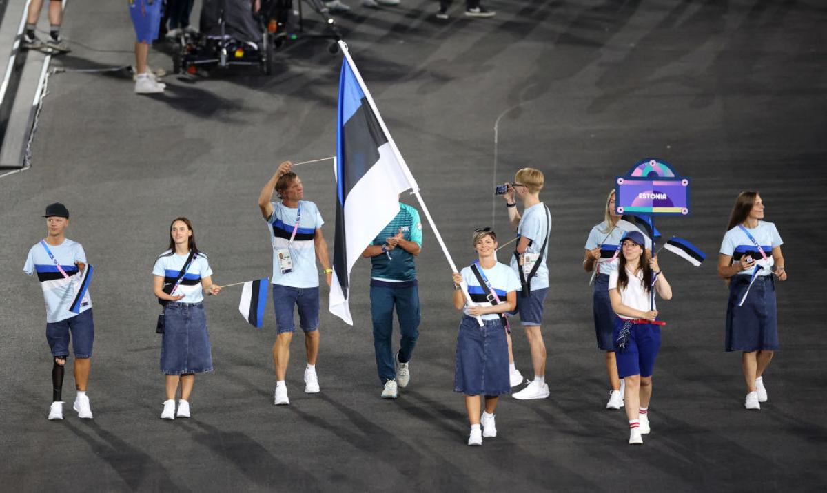 Seven male and female athletes take part in the Parade Of Nations at the Paris 2024 Opening Ceremony. A female athlete is carrying the Estonian flag.